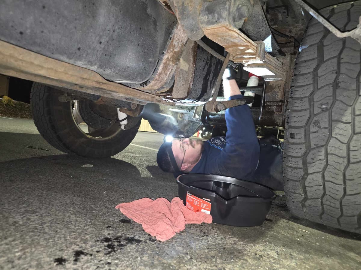 Technician working under a truck with a flashlight at Just Right Automotive